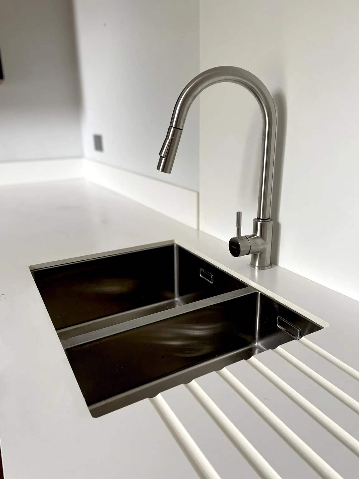 Kitchen sink and mixer tap set into a white worktop.